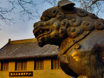 Low angle view of sculpture on building against sky