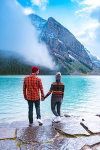 People standing on mountain against sky during winter