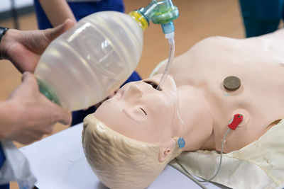 Midsection of paramedics practicing with dummy at hospital