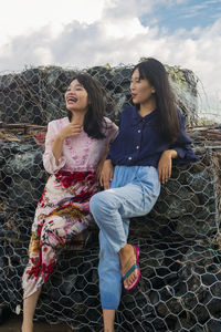 Young woman sitting by chainlink fence