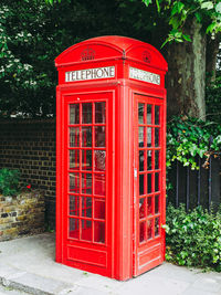 Red telephone booth against trees