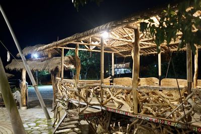 Chairs and table by swimming pool against sky at night