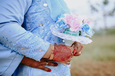 Midsection of bride holding bouquet