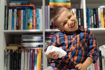 Smiling boy with open book in shelf