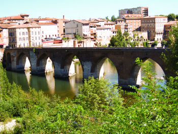 Arch bridge over river amidst buildings in city