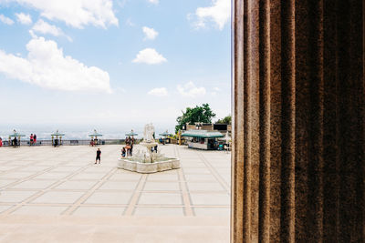 People on street by temple against sky