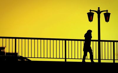 Silhouette of man on railing at sunset