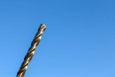 Low angle view of metal against clear blue sky