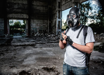 Man wearing gas mask standing under bridge