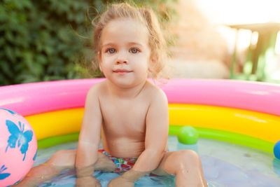 Portrait of cute baby girl sitting in swimming pool