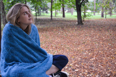 Young woman wearing towel looking up while sitting at park