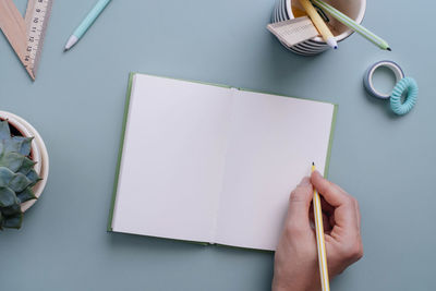 Cropped hand writing in book on table