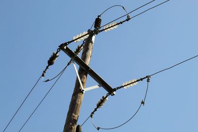 Low angle view of power lines against clear blue sky