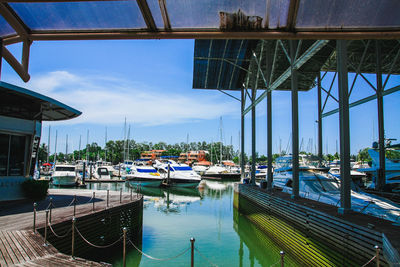 Boats moored at harbor against sky