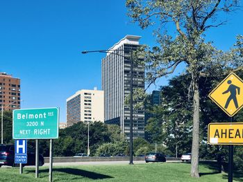 Information sign on road by city against sky