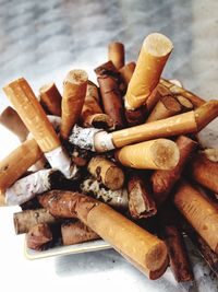 Close-up of cigarette butts in ashtray on table