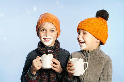 Portrait of boy with brother having cream against sky during snowfall