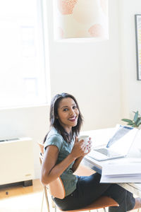 Happy woman having coffee while working at home office