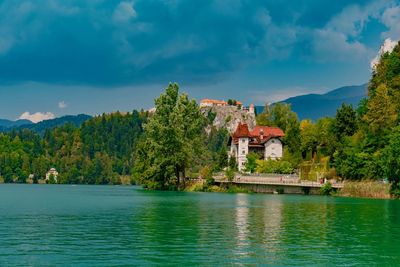 House on lake by building against sky