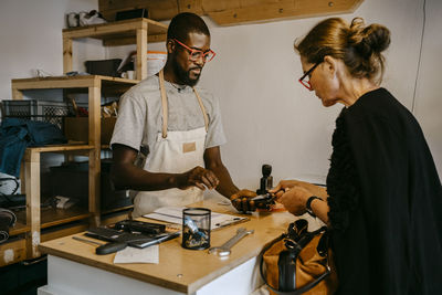 Senior customer making online payment to ale owner in bicycle shop