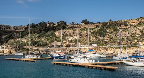 Boats moored in harbor against clear blue sky