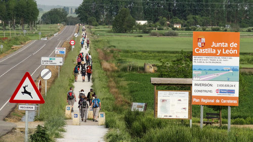 Rear view of people walking on footpath amidst field