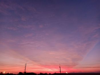 Low angle view of silhouette electricity pylon against dramatic sky