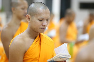 Close-up of monks reading books while sitting in temple