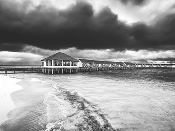 View of pier on beach against cloudy sky