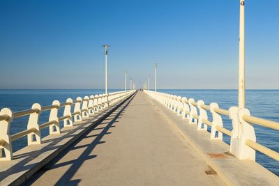 Pier over sea against clear blue sky