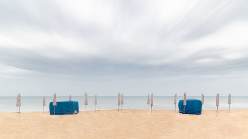 Deck chairs on beach against sky