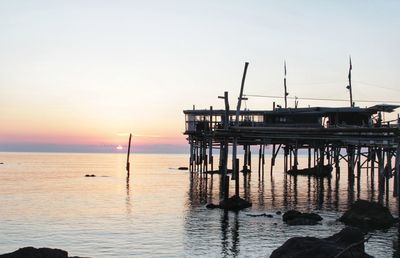 Pier on sea against sky at sunset