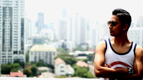 Man wearing sunglasses while standing against cityscape