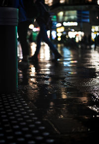 Low section of wet walking on illuminated street during rainy season