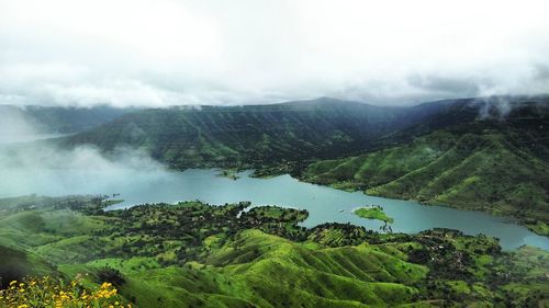 Scenic view of river and green mountains against sky