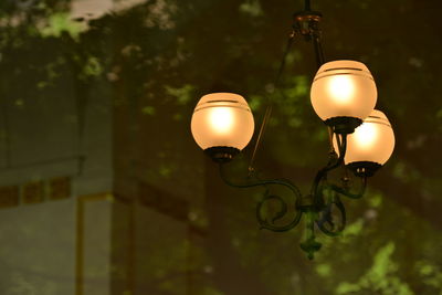 Low angle view of illuminated chandelier seen through glass