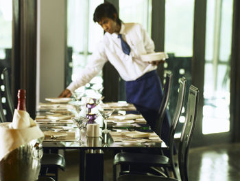 Male waiter setting dining table in restaurant