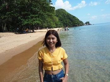 Portrait of smiling young woman standing by sea