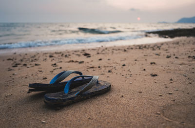 High angle view of shoes on sand at beach against sky