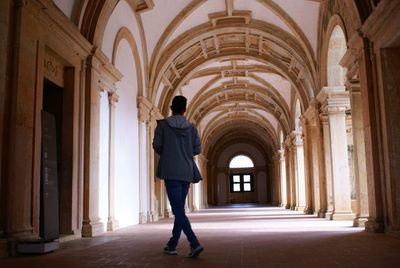 Rear view of man walking in corridor of building