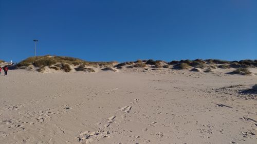 Scenic view of desert against clear blue sky