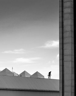 Silhouette man standing on building roof against sky