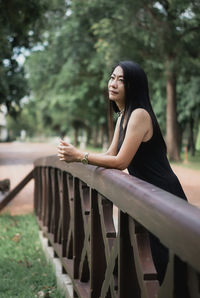 Portrait of young woman standing against trees