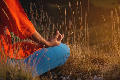 Young slim woman in a lotus position in nature in the mountains, close-up sitting in the grass at