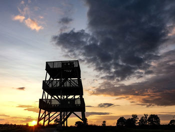Low angle view of silhouette water tower against sky during sunset