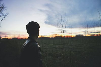 Man standing on field against sky during sunset