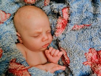 A happy newborn baby peacefully sleeping on a blue and red blanket