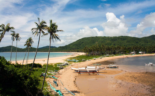 Outrigger boats moored at beach against sky