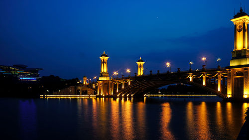 Illuminated bridge over river against sky at night