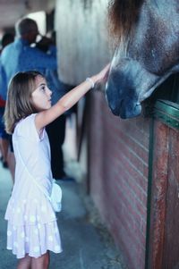 Full length of girl standing outdoors with horse